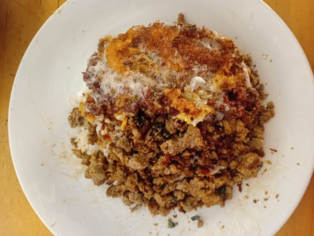 Würziges Fleisch mit einem frittierten Ei servieren. Das ist Kra Pau Nuer.